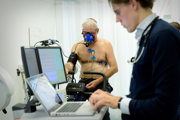 Een patient zit op een fietsergometer voor de inspanningstest terwijl de arts de uitslagen van de meetinstrumenten in de gaten houdt