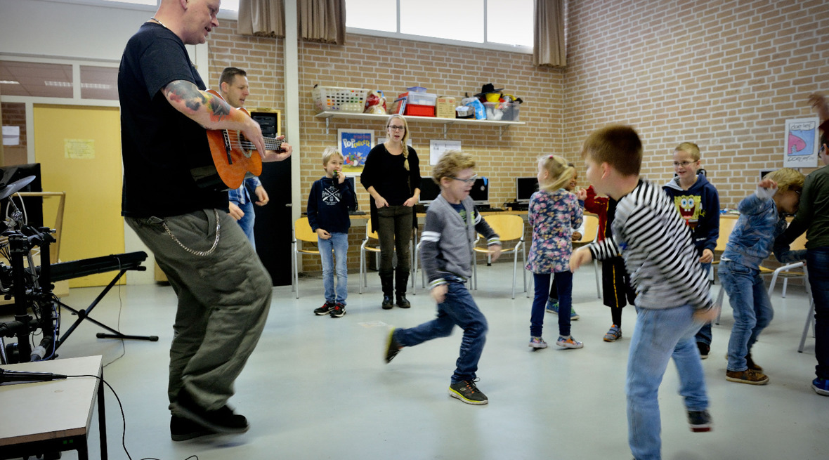 Kinderen dansen op muziek gespeeld door een leraar