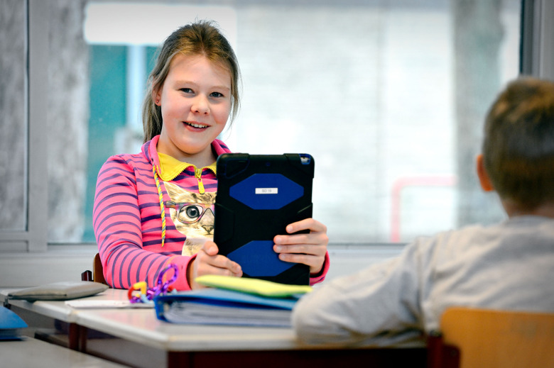Leerling achter haar bureau met een iPad in haar handen