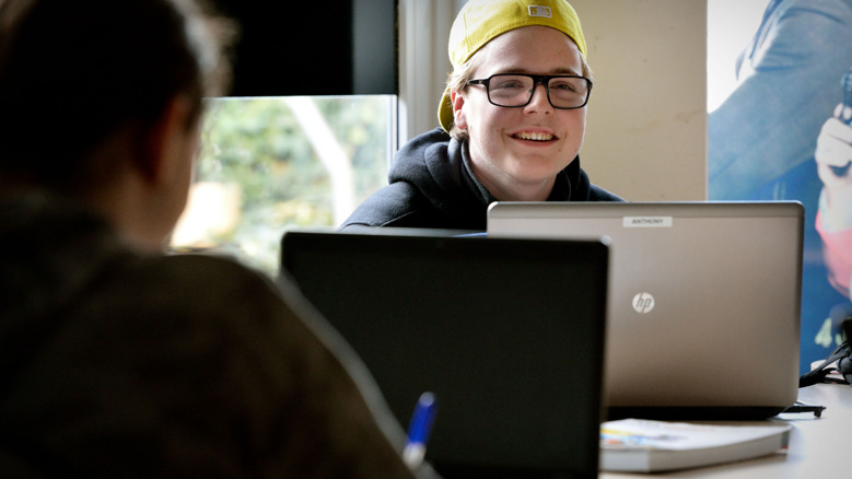 Leerling zit achter zijn bureau met een laptop