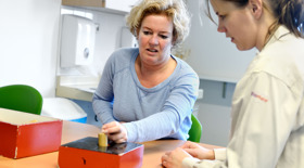 Ergotherapeut geeft aanwijzingen aan patiënt tijdens handtraining