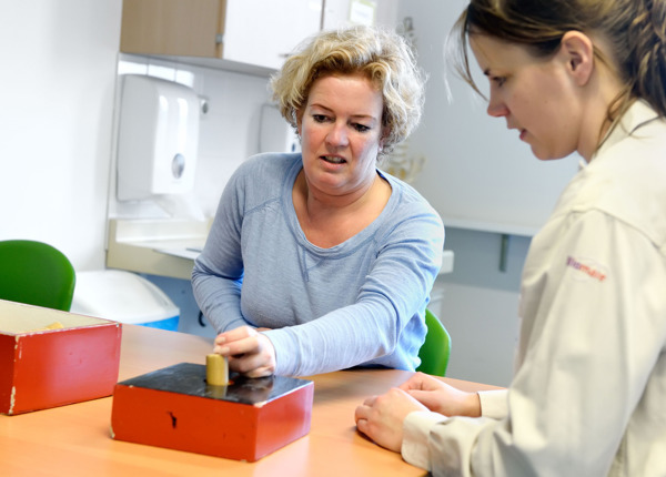 Ergotherapeut geeft aanwijzingen aan patiënt tijdens handtraining
