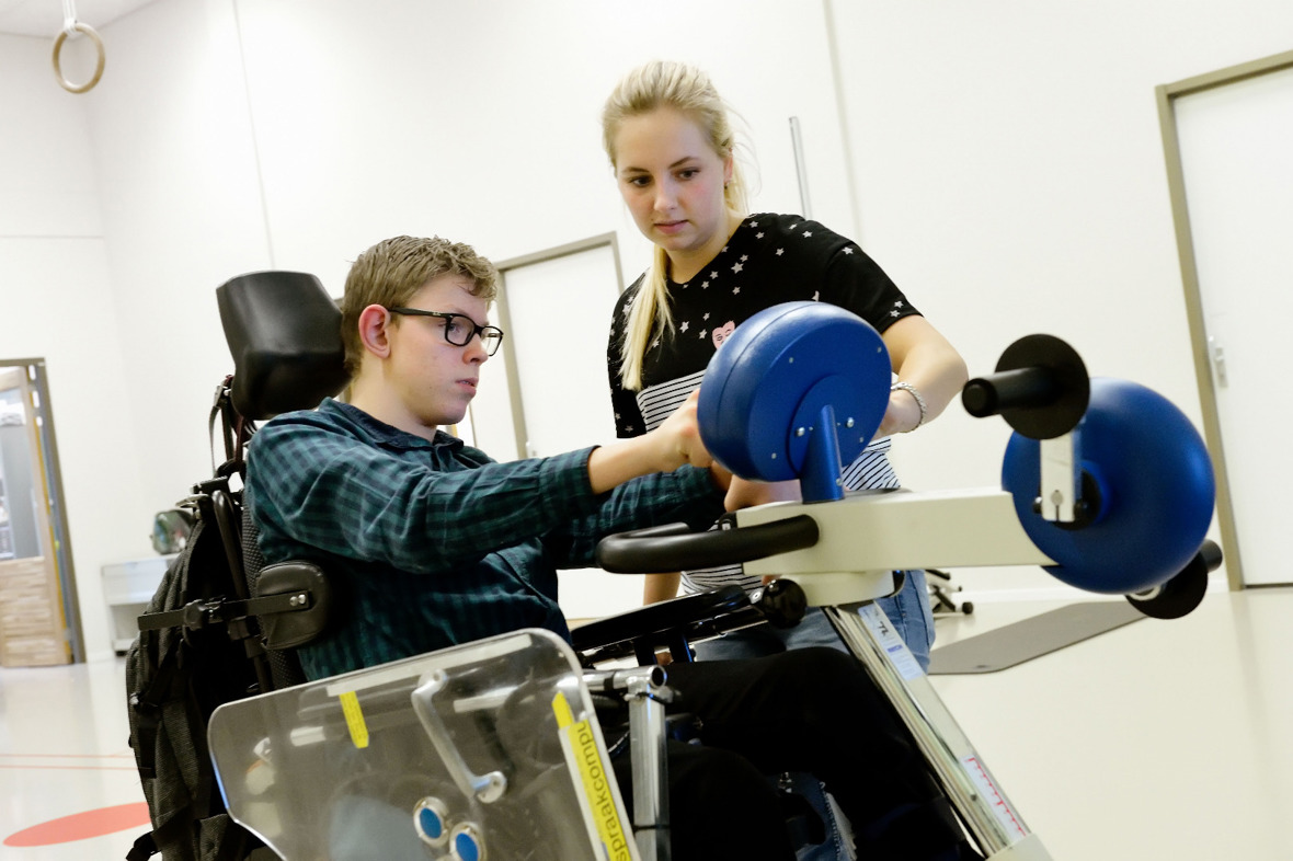 Therapeut helpt cliënt in rolstoel met electronica