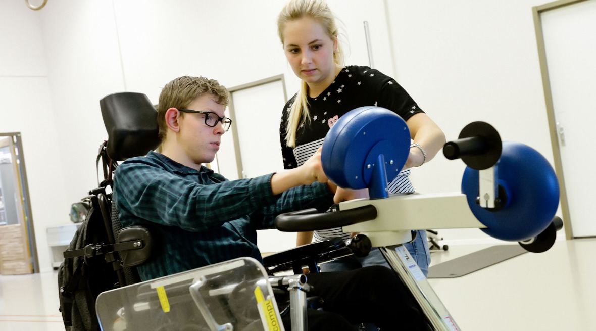 Therapeut helpt cliënt in rolstoel met electronica