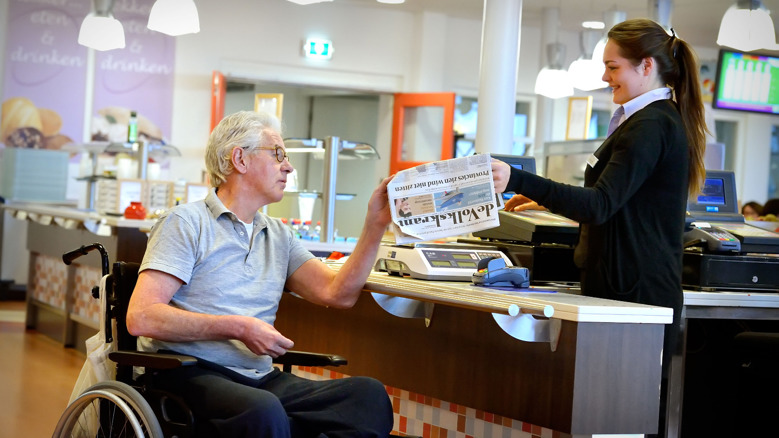 Cliënt koopt krant in Orangerie