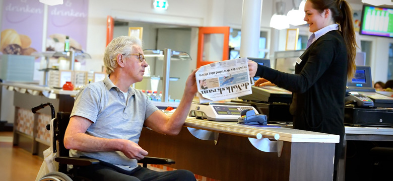 Cliënt koopt krant in Orangerie