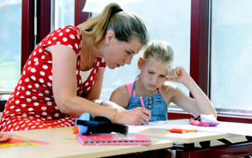 Leerling aan bureau wordt begeleid door docent