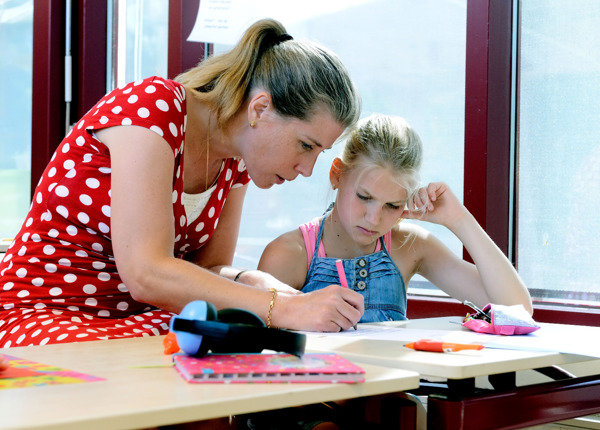 Leerling aan bureau wordt begeleid door docent