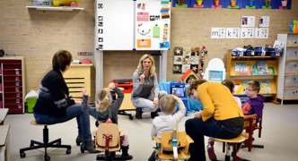 Leerlingen in een kring luisteren aandachtig naar docent