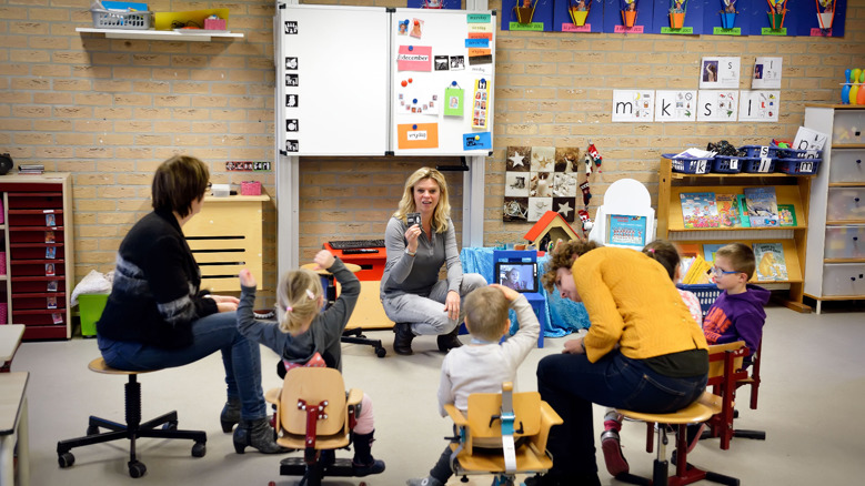 Leerlingen in een kring luisteren aandachtig naar docent