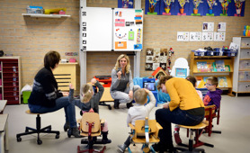 Leerlingen in een kring luisteren aandachtig naar docent